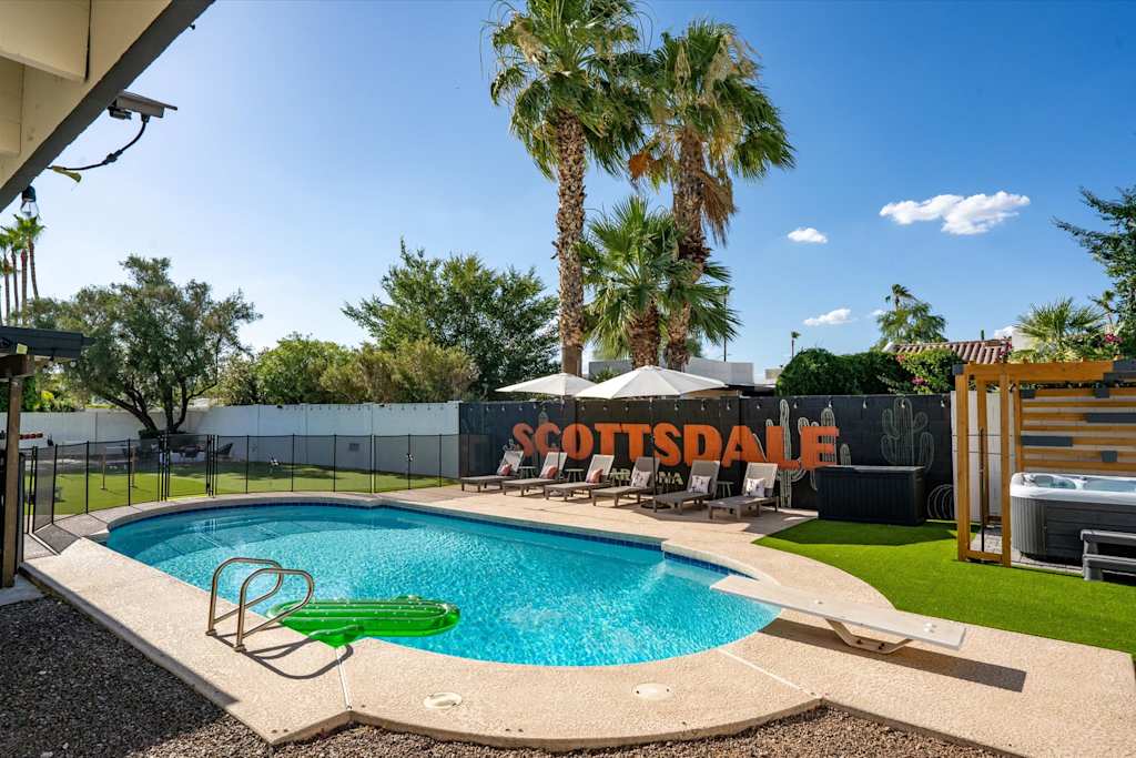 The Sunkiss — backyard swimming pool with diving board, sun loungers, palm trees, and a hot tub