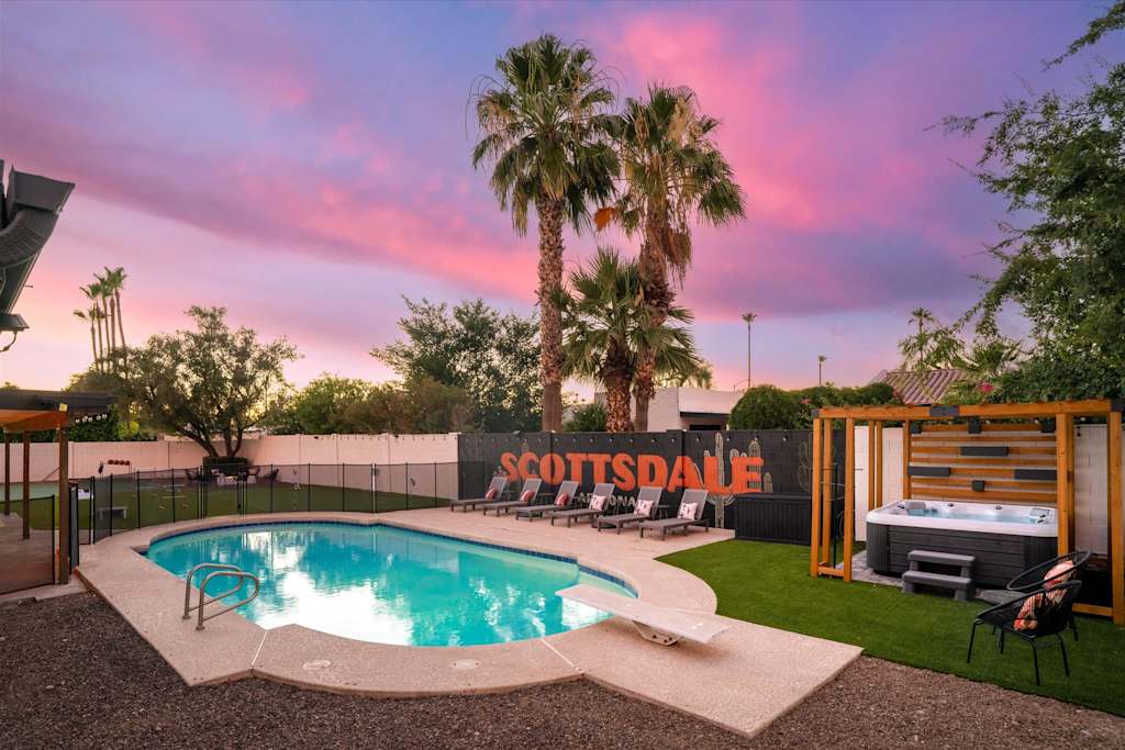 The Sunkiss — backyard at dusk with a swimming pool, diving board, hot tub, lounge chairs, and palm trees