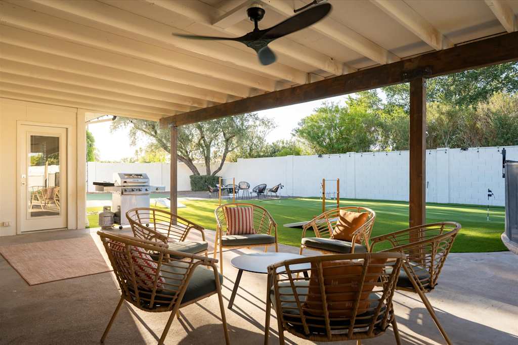 The Sunkiss — covered patio with wicker armchairs, coffee table, ceiling fan, and view of the backyard