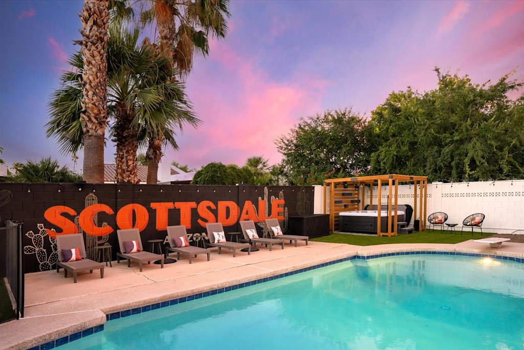 The Sunkiss — backyard swimming pool with lounge chairs and a hot tub under palm trees at sunset