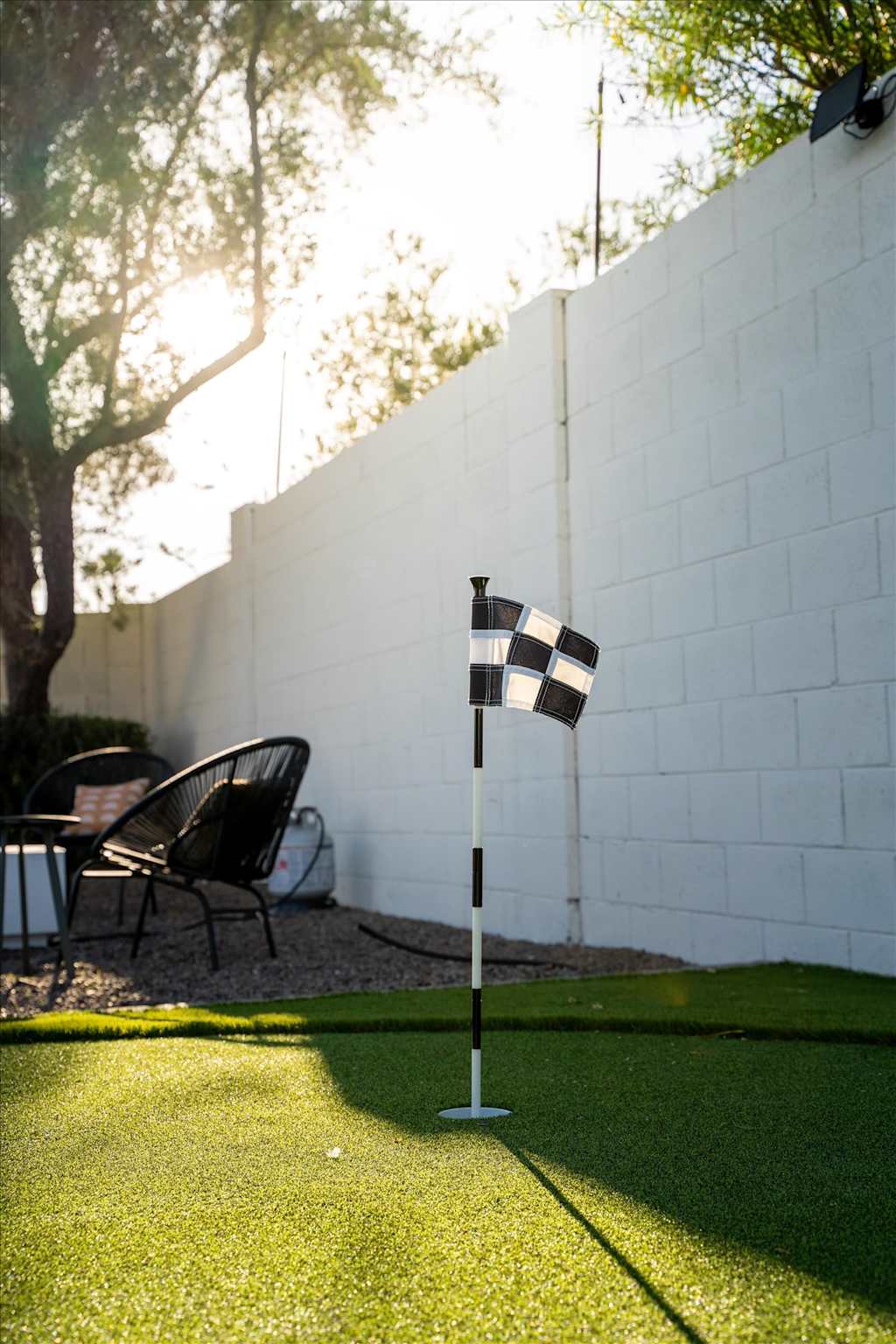 The Sunkiss — checkered golf flag on an outdoor putting green next to a white cinder block wall