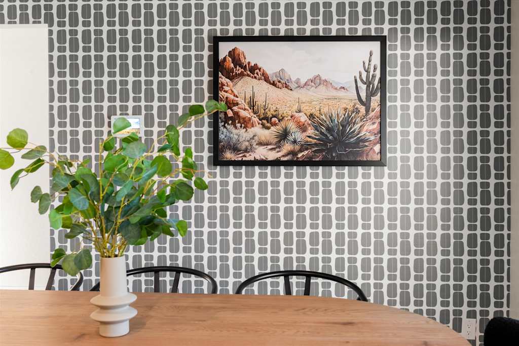The Sunkiss — dining table with plant centerpiece against a patterned wallpaper wall featuring framed desert artwork
