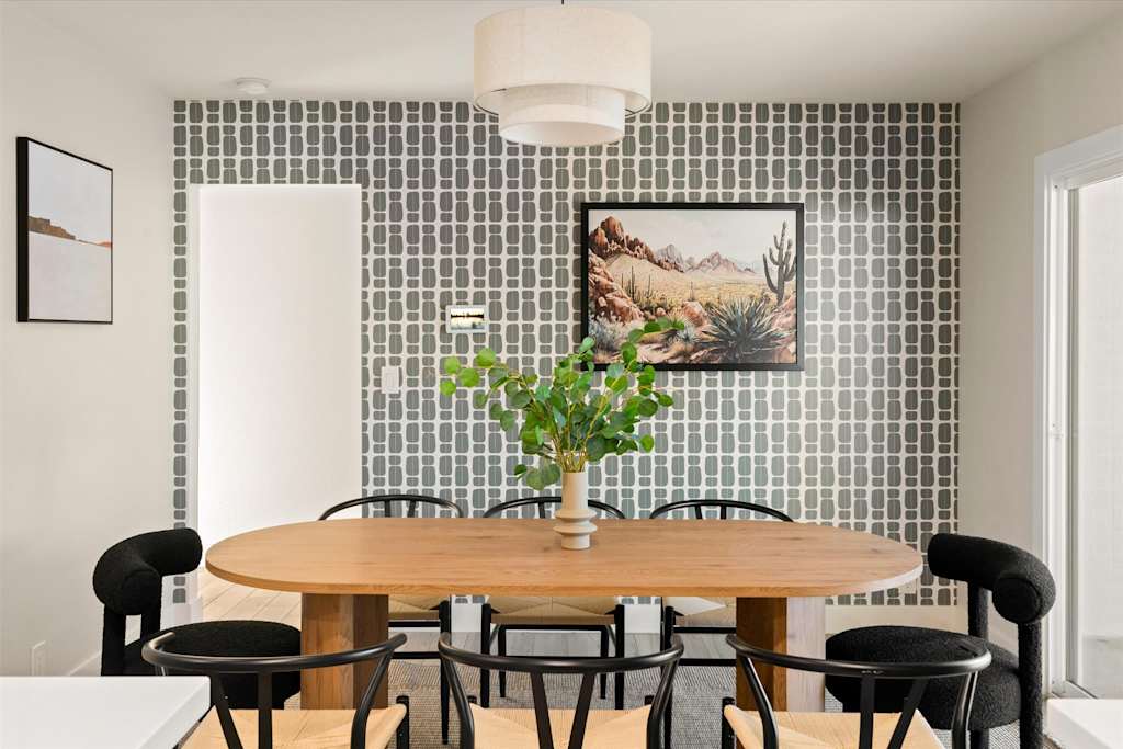 The Sunkiss — dining room with an oval wooden table, black chairs, patterned accent wall, and pendant light