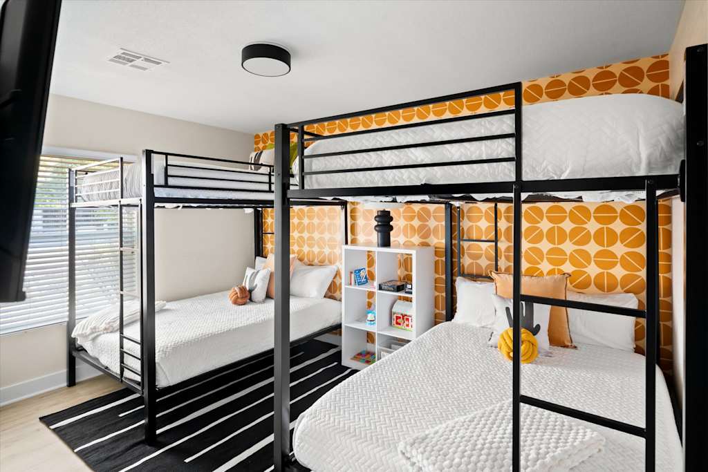 The Sunkiss — bunk room featuring two sets of black metal bunk beds and yellow patterned wallpaper