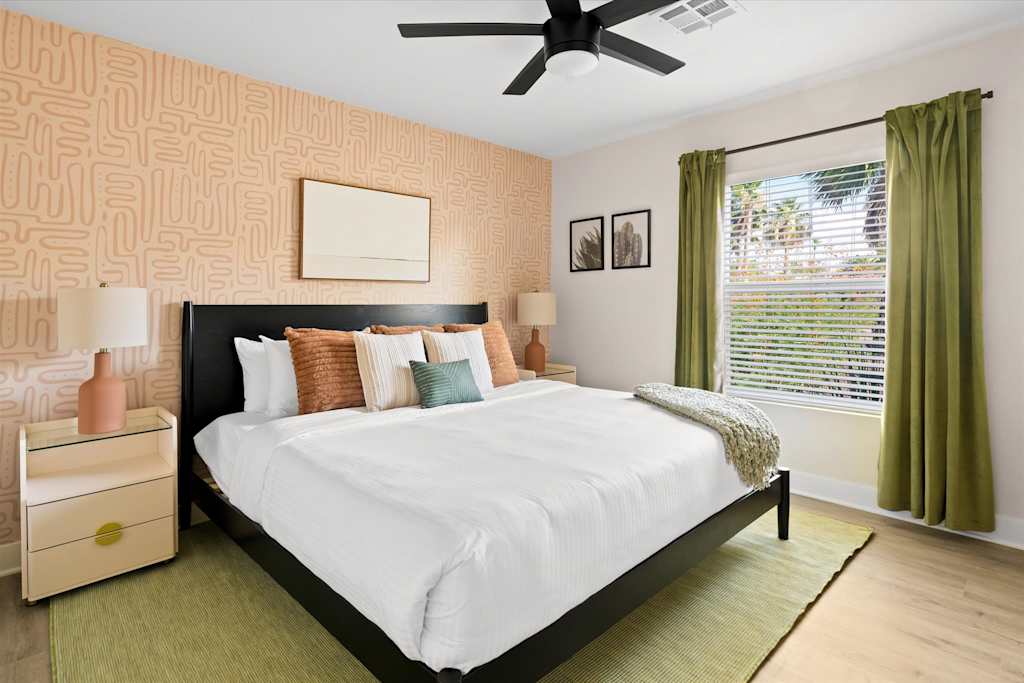 The Sunkiss — bedroom featuring a black bed, pink patterned wallpaper, green rug, ceiling fan, and window