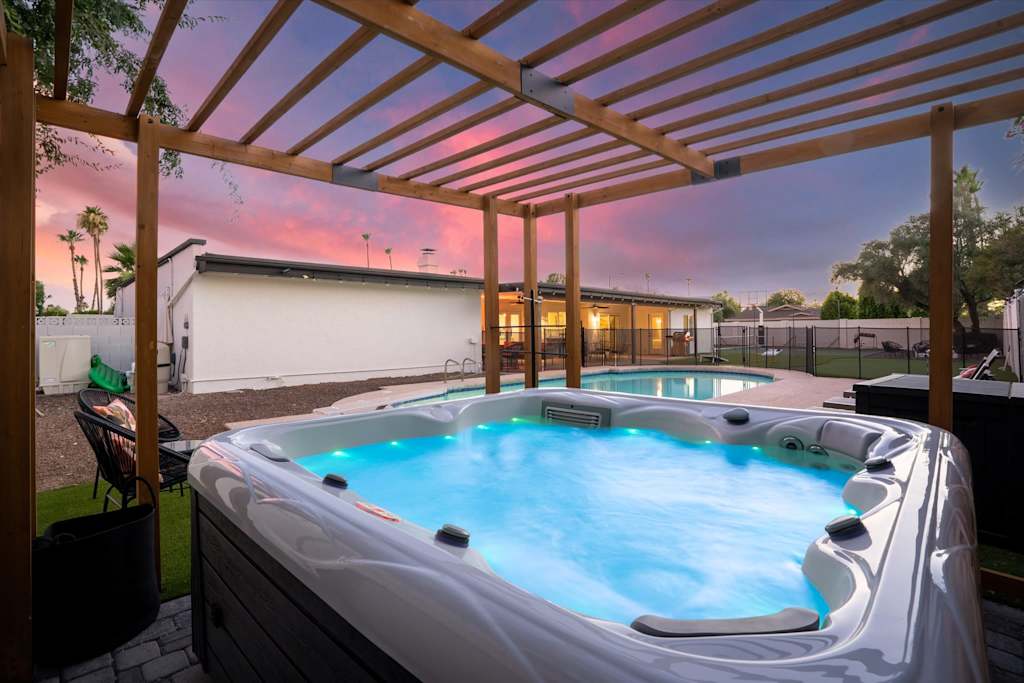 The Sunkiss — outdoor hot tub with illuminated water under a wooden pergola in a backyard at dusk
