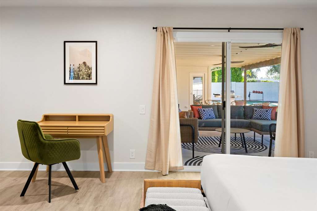 The Sunkiss — bedroom view featuring wooden desk with green armchair next to sliding glass doors leading to patio