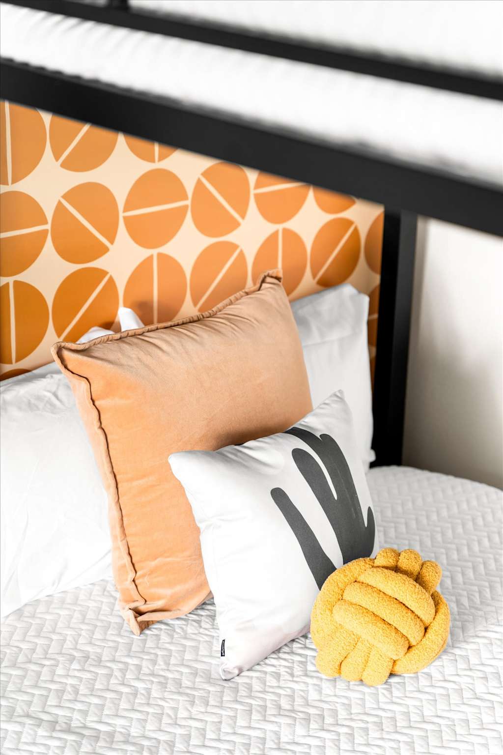 The Sunkiss — bunk bed with orange geometric headboard, decorative throw pillows, and a yellow knot pillow