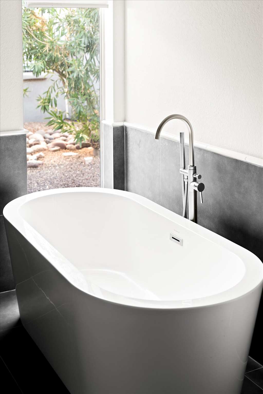 The Sunkiss — modern white freestanding soaking bathtub with a tall chrome floor-mounted faucet