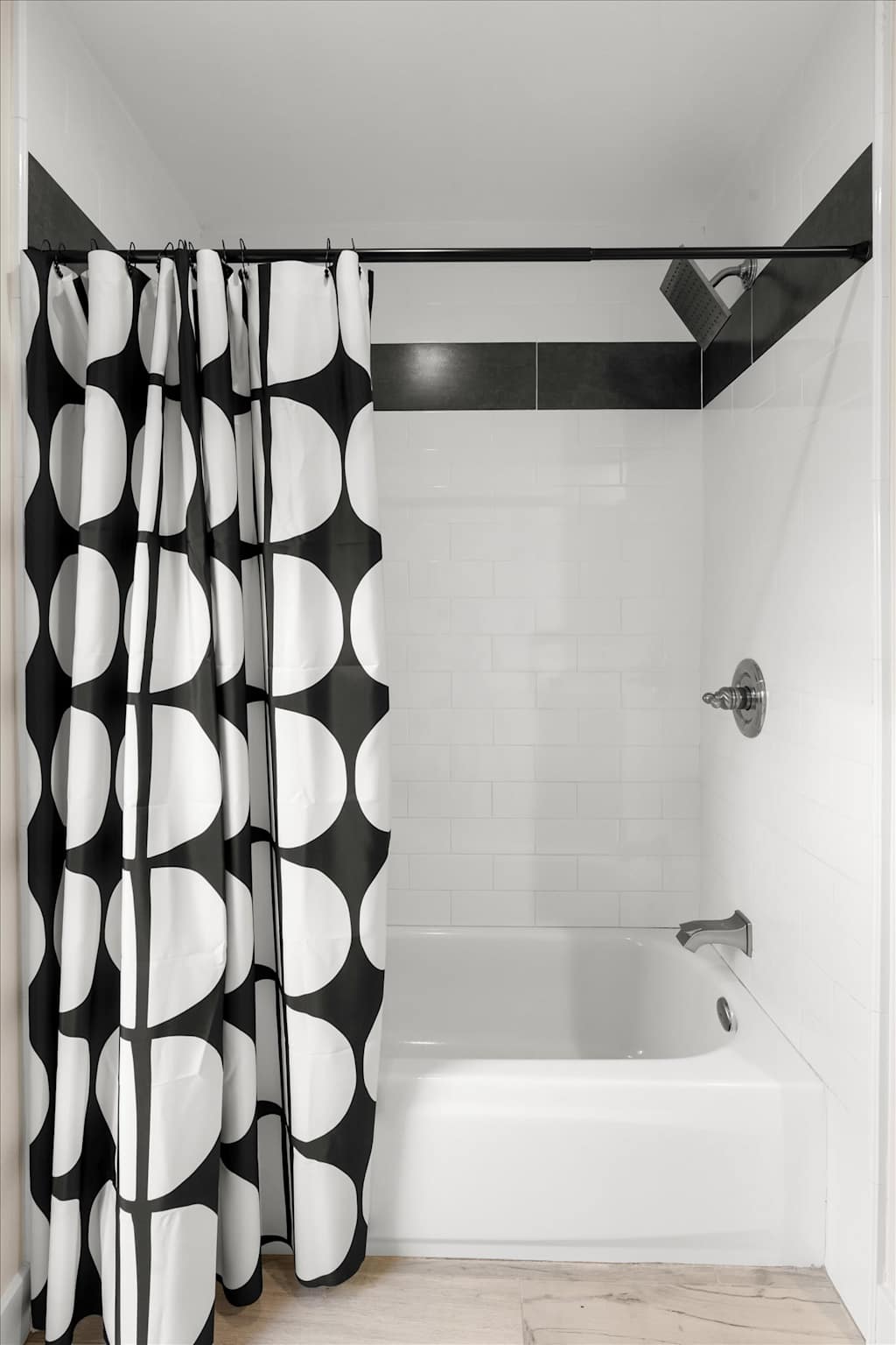 The Sunkiss — bathtub and shower combination with white tile and a bold black-and-white patterned shower curtain