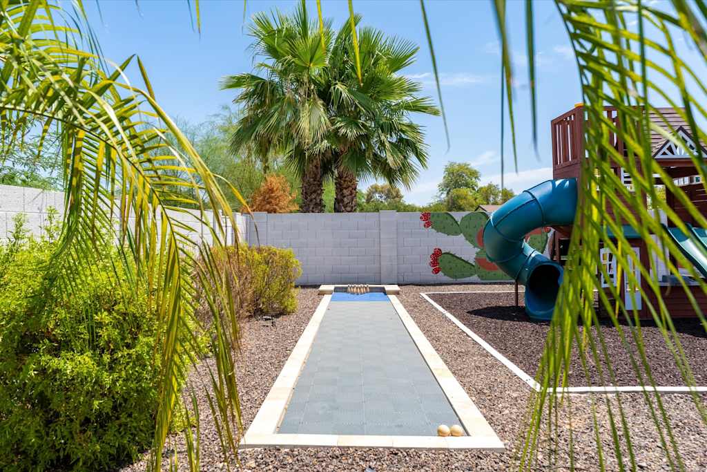 The Scottsdale Social — outdoor bowling lane framed by palm fronds next to a children's play structure and palm trees