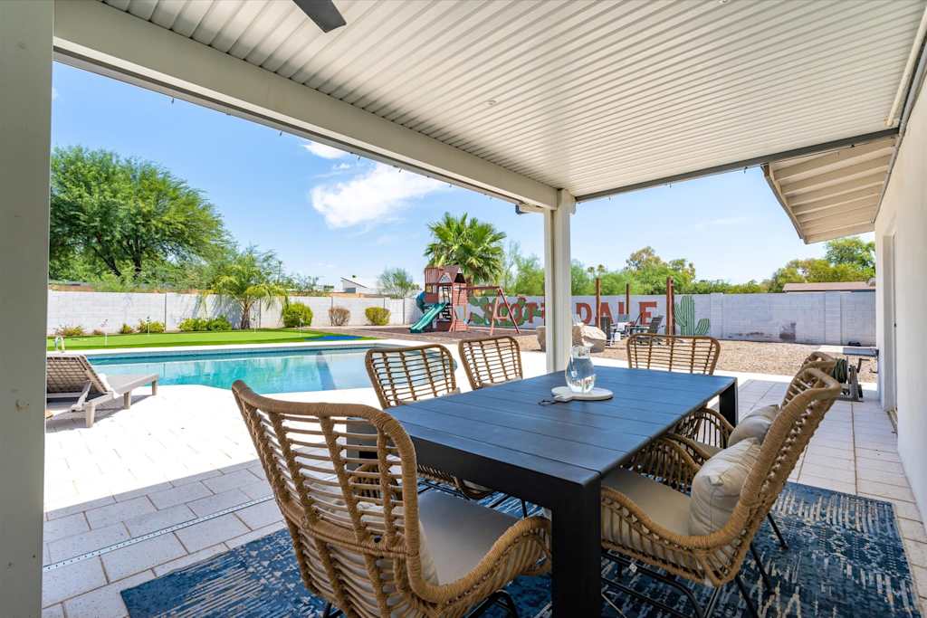 The Scottsdale Social — covered patio with dining table and chairs overlooking a swimming pool and backyard