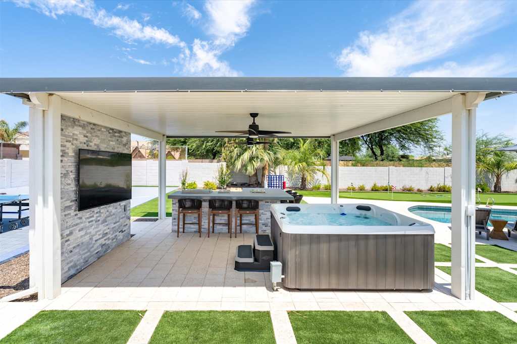 The Scottsdale Social — covered outdoor patio featuring a hot tub, bar seating, ceiling fan, and wall-mounted television