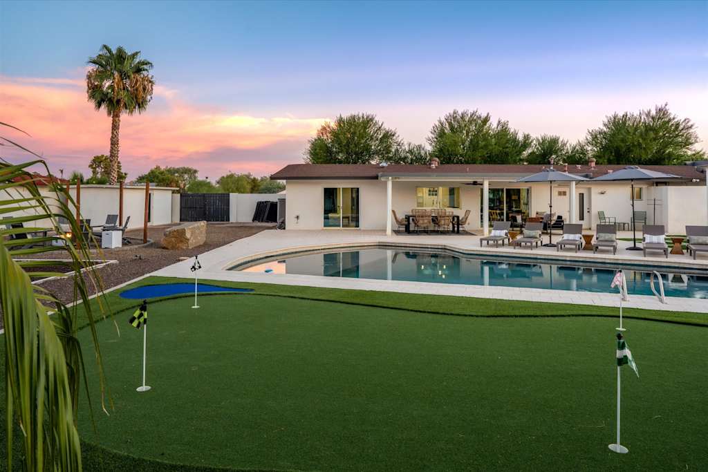 The Scottsdale Social — putting green in the foreground with a swimming pool, lounge chairs, and house at sunset