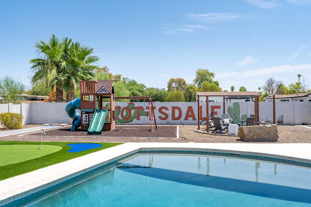 The Scottsdale Social — backyard swimming pool with a children's play structure and painted wall in the background