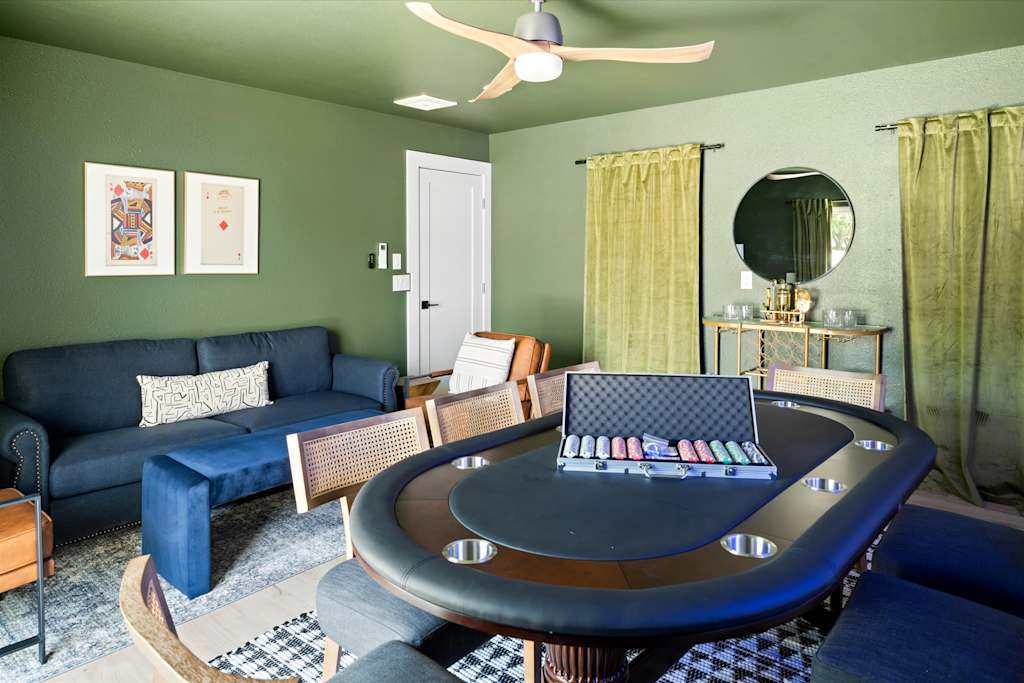 The Scottsdale Social — green game room featuring a poker table with chips, blue sofa, and bar cart