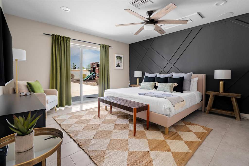 The Scottsdale Social — spacious bedroom with a dark geometric accent wall, king bed, patterned rug, and sliding glass door