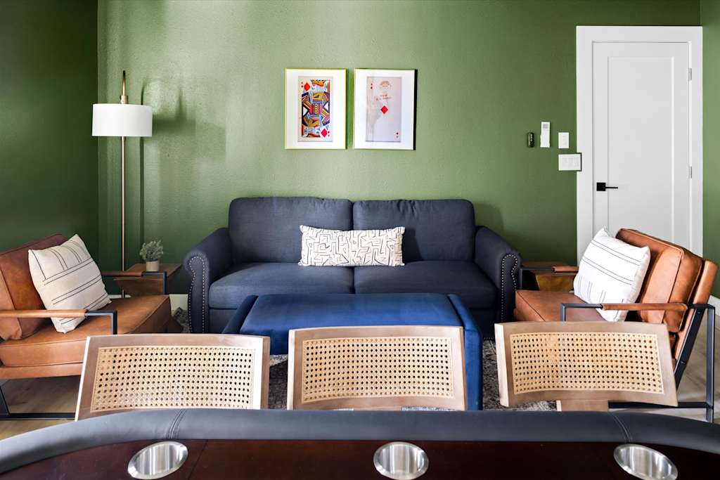 The Scottsdale Social — seating area with green wall, dark sofa, leather armchairs, and playing card artwork