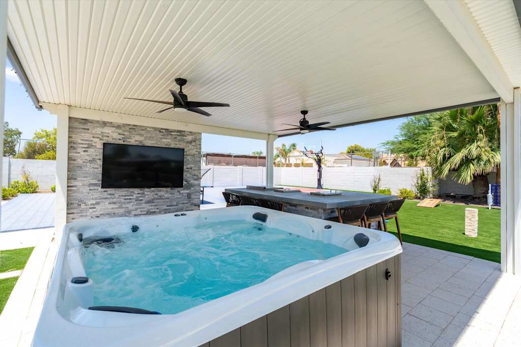 The Scottsdale Social — covered patio featuring a hot tub, bar counter with stools, and outdoor television