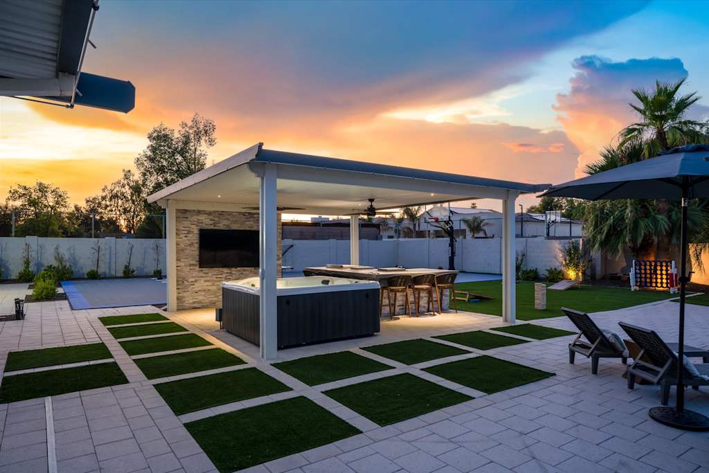 The Scottsdale Social — backyard patio at sunset with a covered pavilion, hot tub, outdoor bar, and lounge chairs
