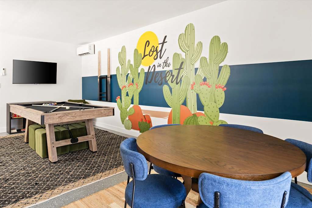 The Scottsdale Social — game room with a pool table, round table with blue chairs, and cactus wall mural