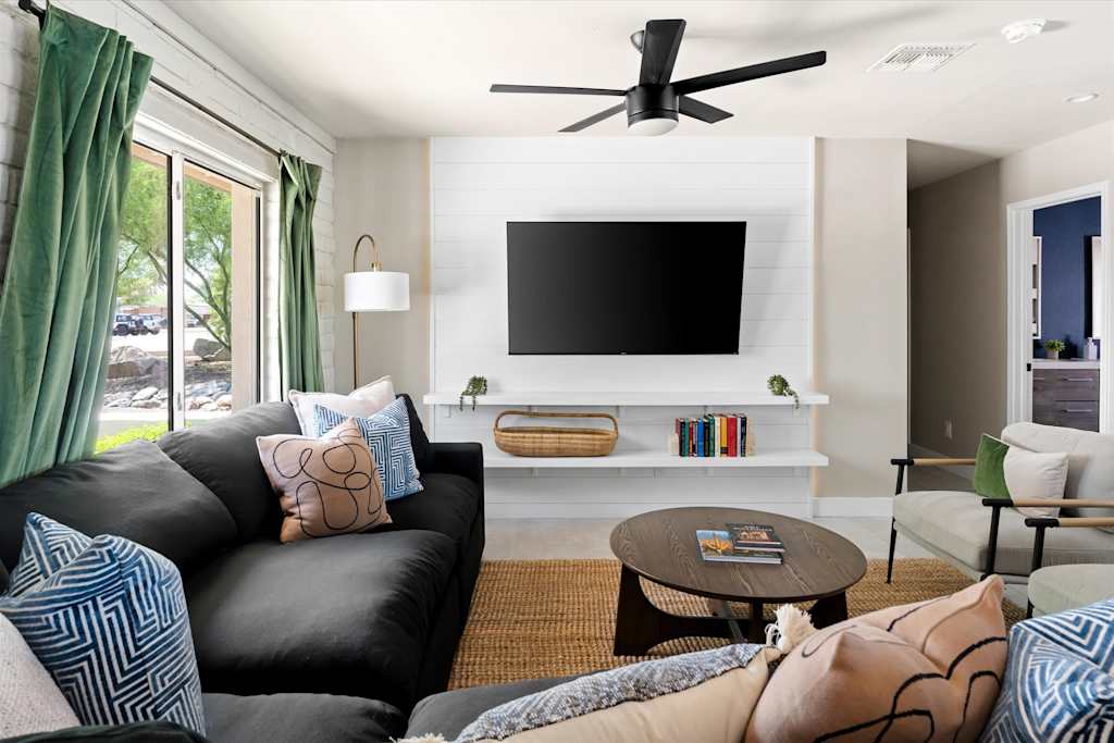 The Scottsdale Social — living room with dark sectional sofa, round coffee table, and wall-mounted tv on white shiplap