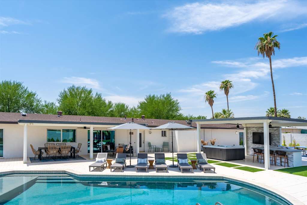 The Scottsdale Social — backyard featuring a swimming pool, row of lounge chairs, covered patio dining, and hot tub area