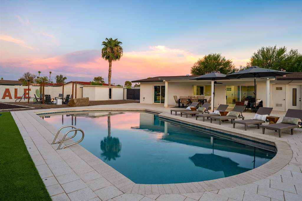 The Scottsdale Social — swimming pool with surrounding lounge chairs and patio at dusk under a colorful sky