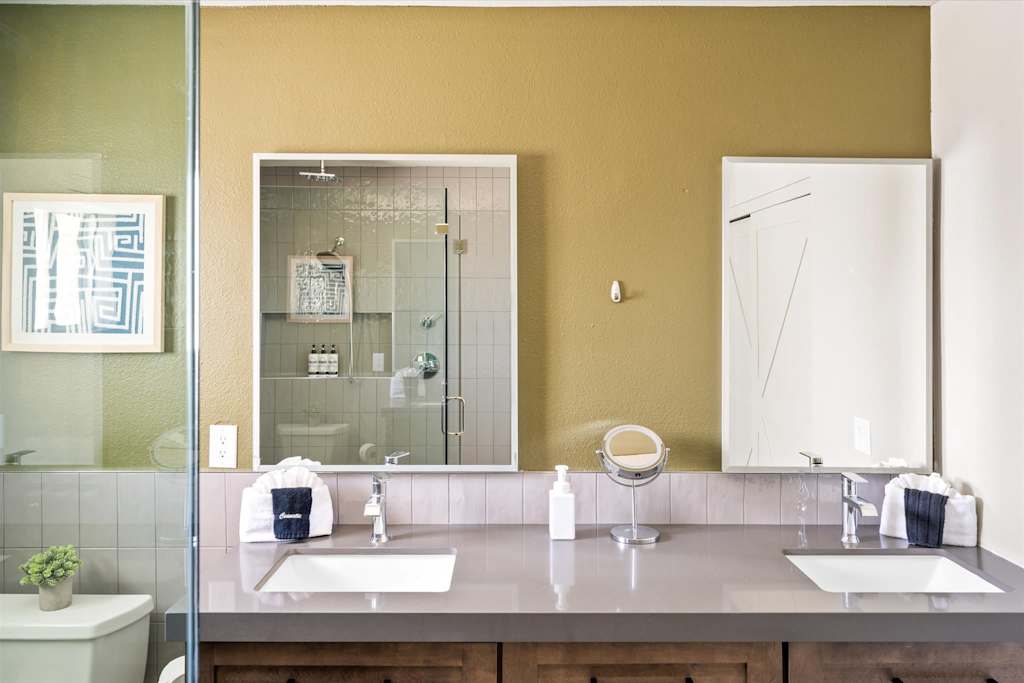 The Scottsdale Social — bathroom vanity with two sinks, two rectangular mirrors, and olive green accent wall