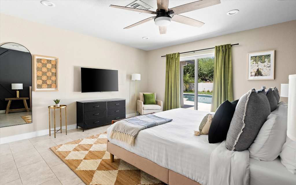 The Scottsdale Social — bedroom with a made bed, wall-mounted tv, dresser, and sliding glass door leading outside