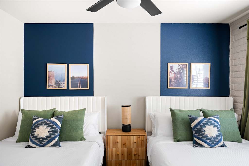 The Scottsdale Social — bedroom with two beds, green pillows, a wooden nightstand, and blue wall accents with framed art