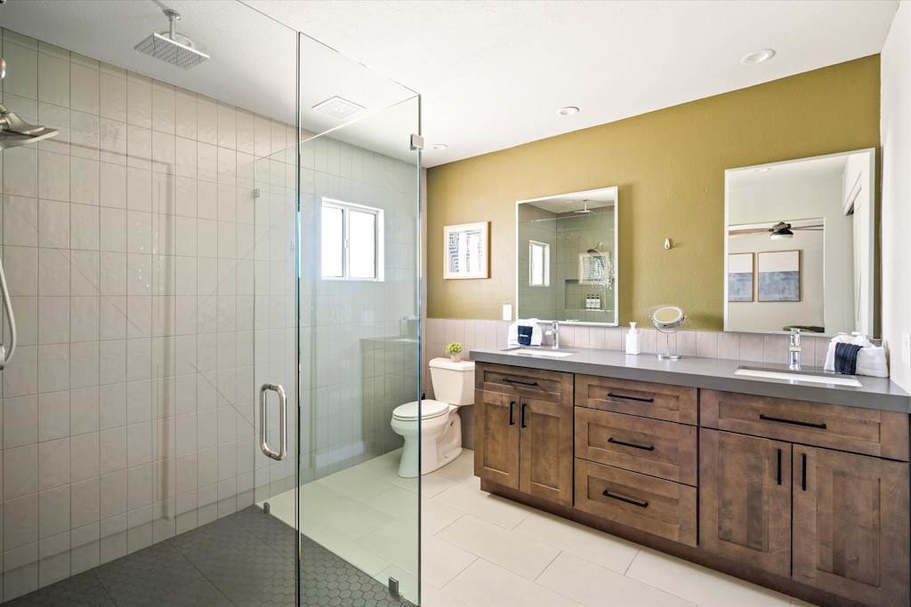 The Scottsdale Social — bathroom with glass walk-in shower, double wooden vanity, large mirrors, and green accent wall