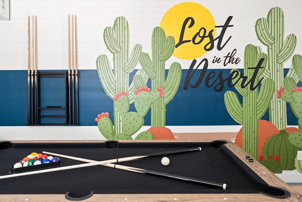The Scottsdale Social — pool table with crossed cues in front of a desert-themed wall mural with painted cacti