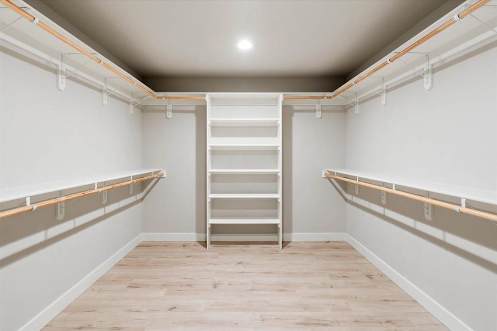 The Scottsdale Social — empty walk-in closet with built-in shelving, hanging rods, and light wood-look flooring