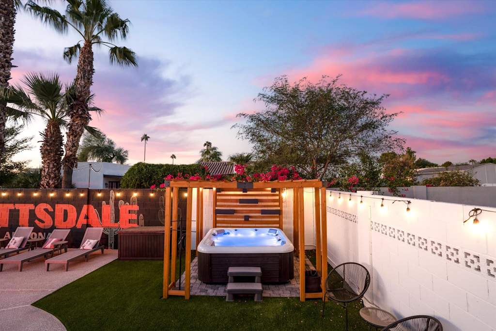 The Sunkiss — hot tub beneath a wooden pergola in a backyard at dusk with string lights