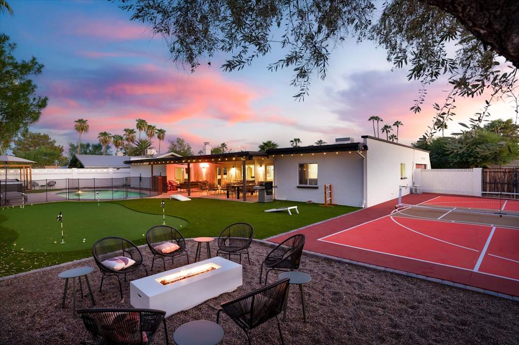 The Sunkiss — backyard with fire pit seating area, pickleball court, and putting green at sunset