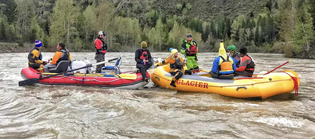 The Evergreen — group of people in two inflatable rafts on a river near forested shores