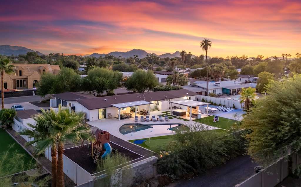 The Scottsdale Social — aerial view of a home's backyard with a swimming pool, putting green, and patio at sunset