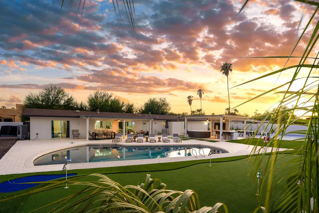 The Scottsdale Social — backyard with a swimming pool, putting green, and covered patio under a sunset sky