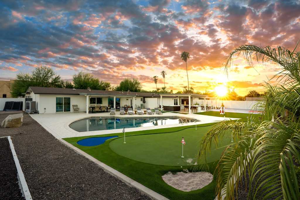 The Scottsdale Social — backyard putting green and sand trap next to a swimming pool at sunset