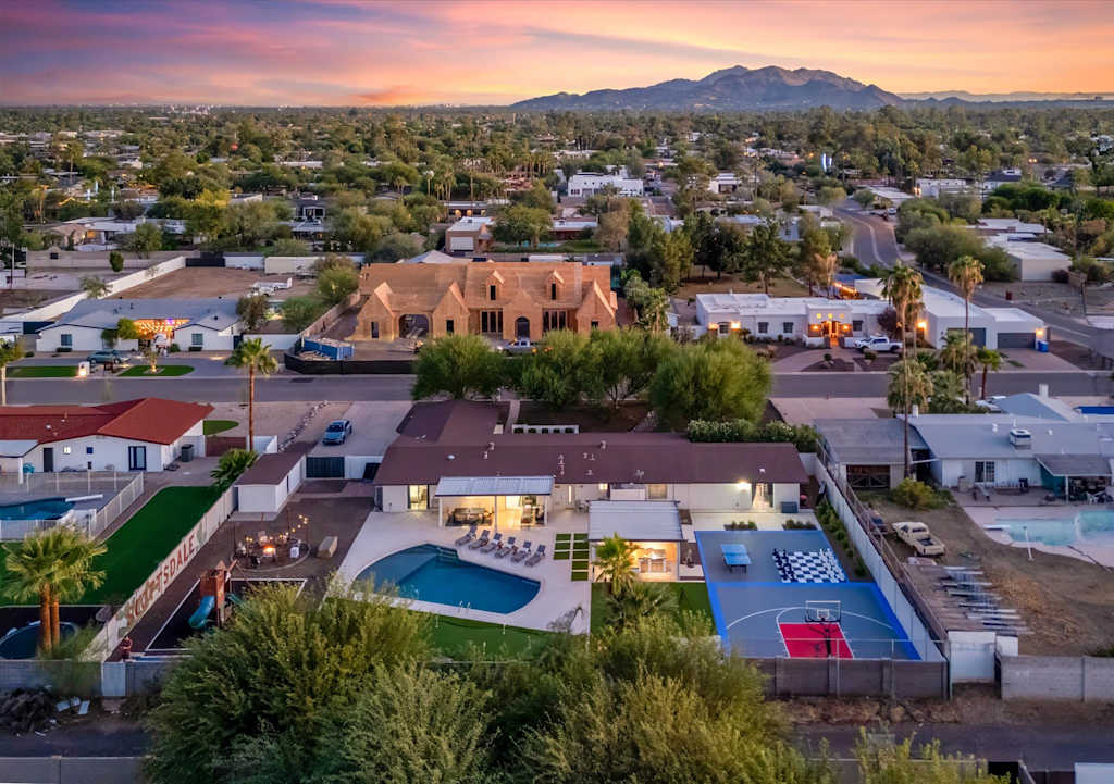 The Scottsdale Social — aerial view of a vacation home backyard with swimming pool, sports court, and mountain sunset views
