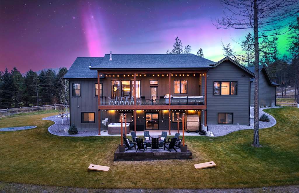 The Evergreen — back exterior of two-story house with deck, patio fire pit, and night sky