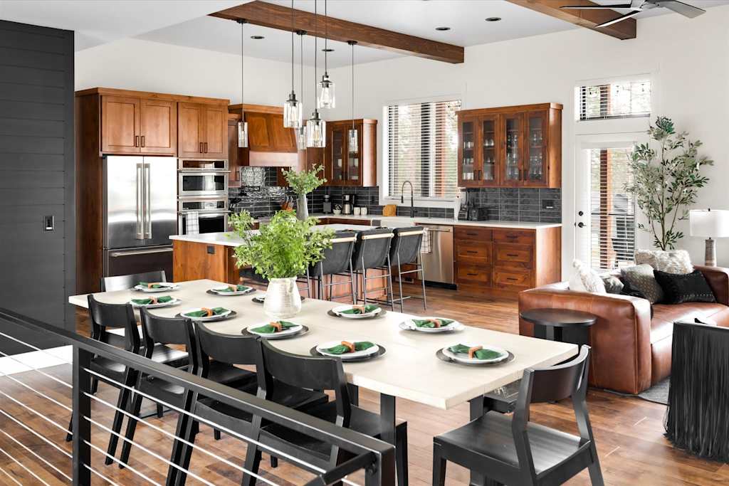 The Evergreen — set dining table in foreground with wood-cabinet kitchen and stainless steel appliances in background