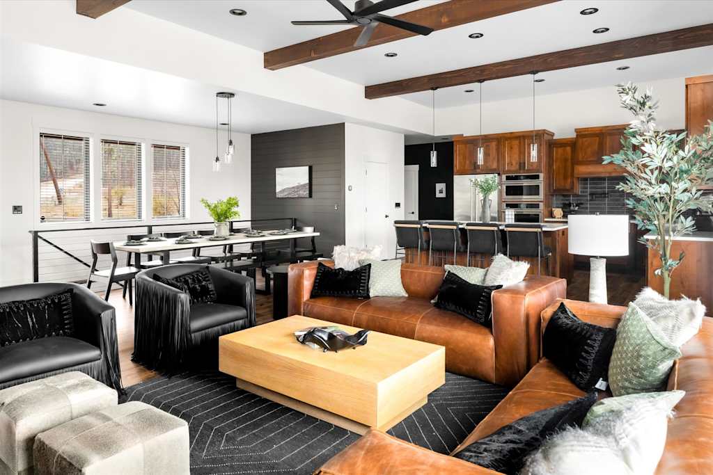 The Evergreen — open-concept living room with leather sofas, light wood coffee table, dining table, and kitchen