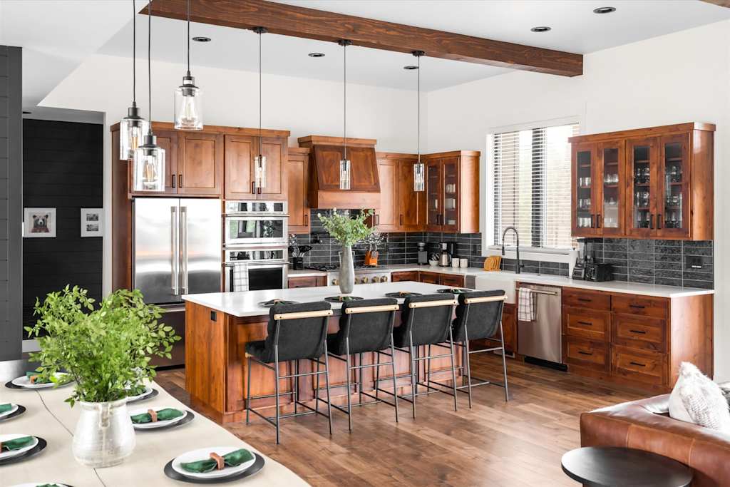 The Evergreen — kitchen featuring wood cabinets, stainless steel appliances, kitchen island with bar stools, and wood beam ceiling