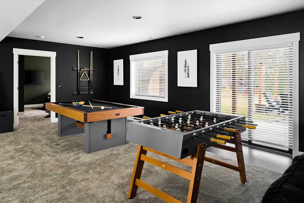 The Evergreen — game room featuring a foosball table, pool table, cue rack, and sliding glass door with blinds