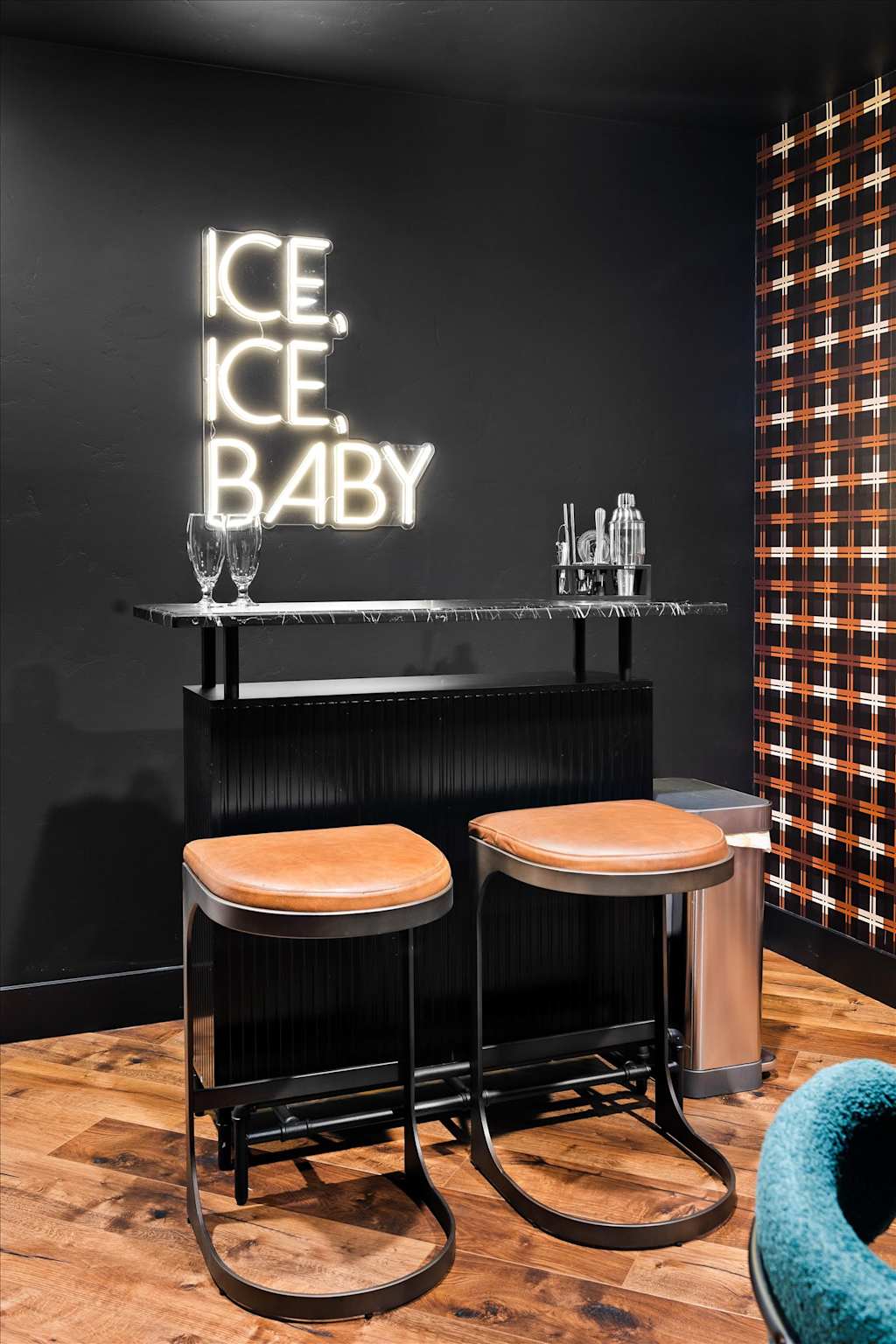 The Evergreen — black home bar setup with leather barstools and a glowing neon sign on the wall