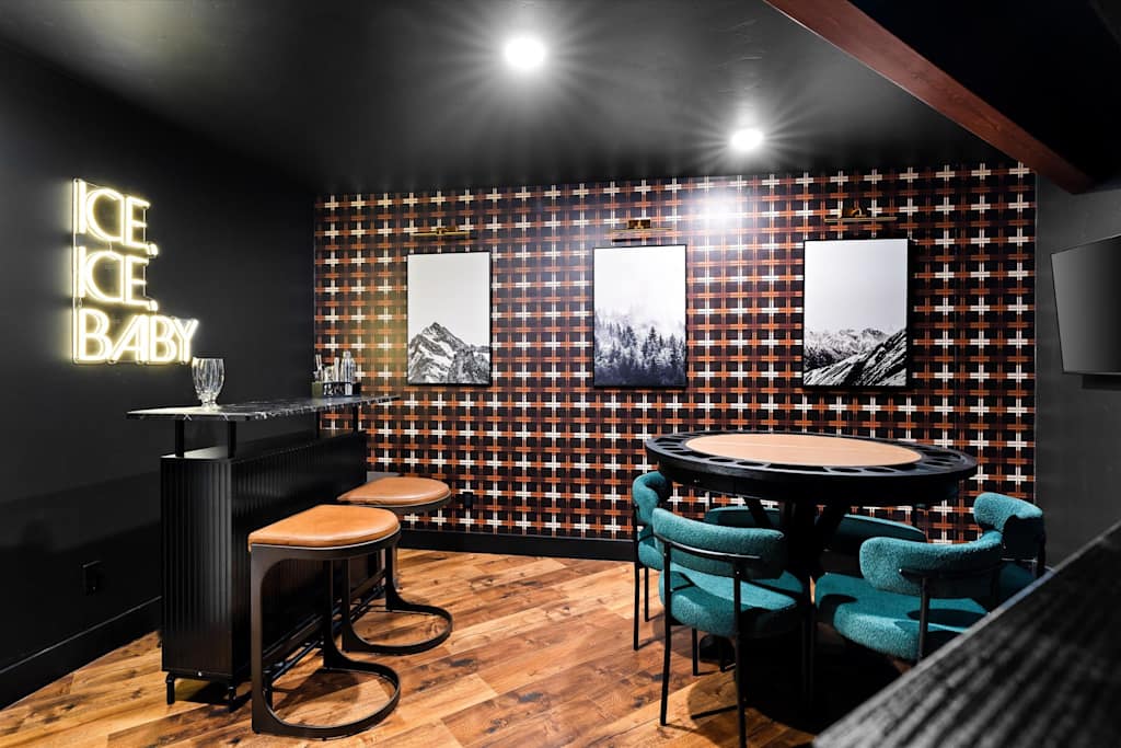 The Evergreen — game room featuring a round poker table with teal chairs, a mini bar, and plaid wallpaper