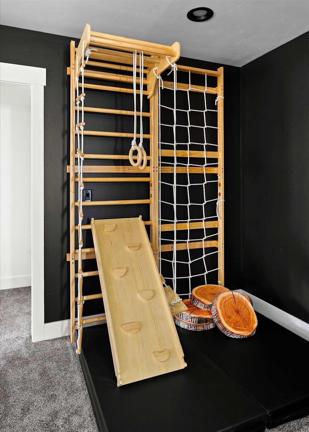 The Evergreen — indoor wooden kids climbing playset with climbing wall, rope net, and wood-patterned floor cushions