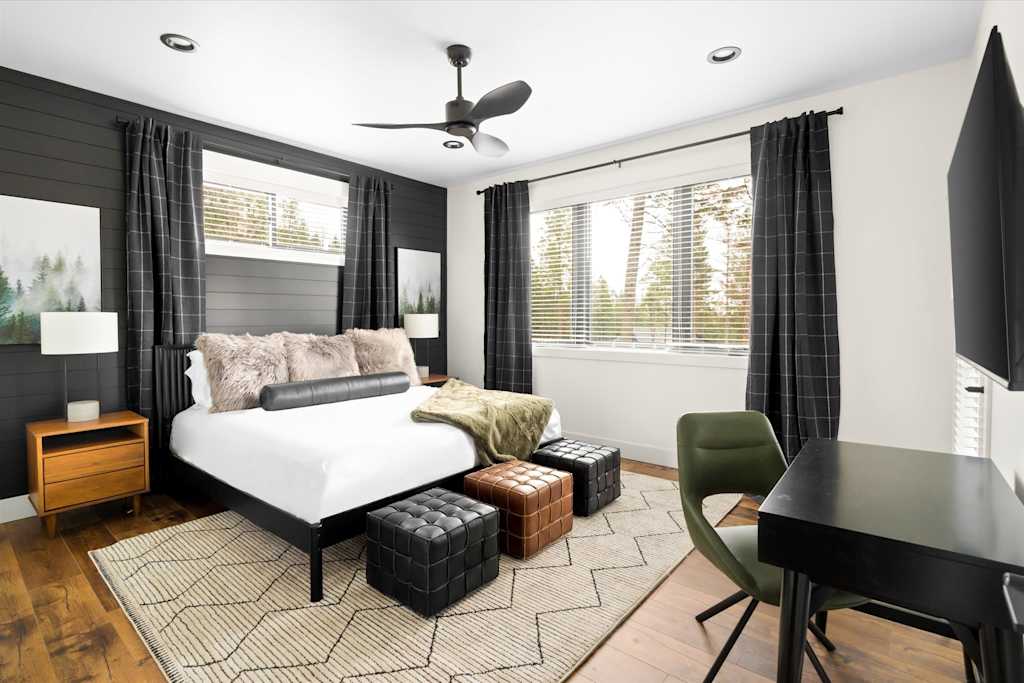 The Evergreen — bedroom featuring a bed with decorative pillows, dark shiplap accent wall, area rug, and desk